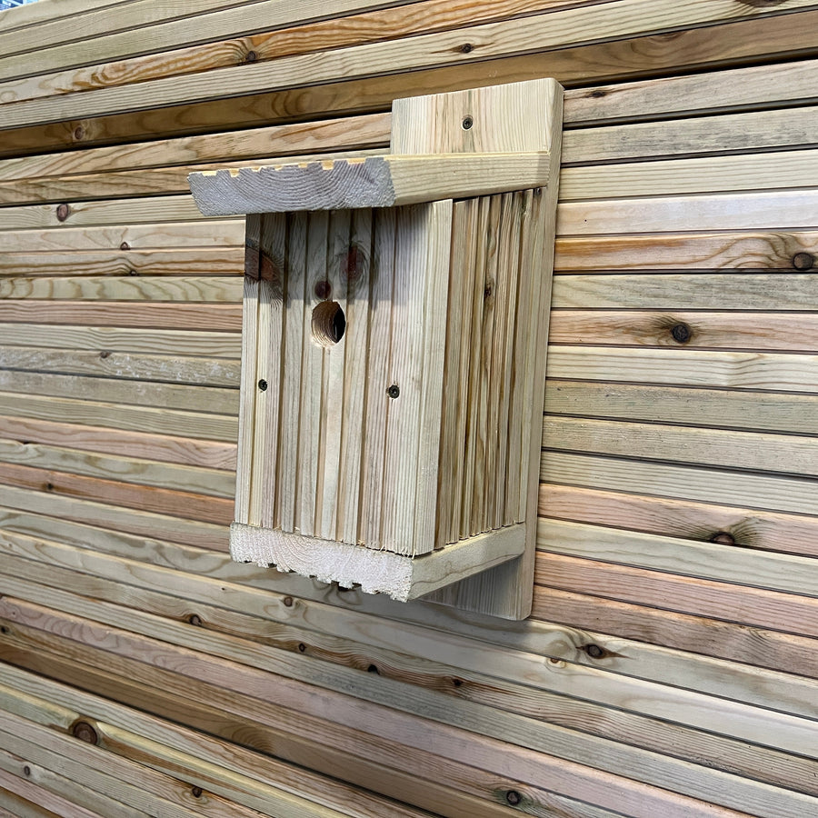 Angled front view of a nesting box mounted against timber boards