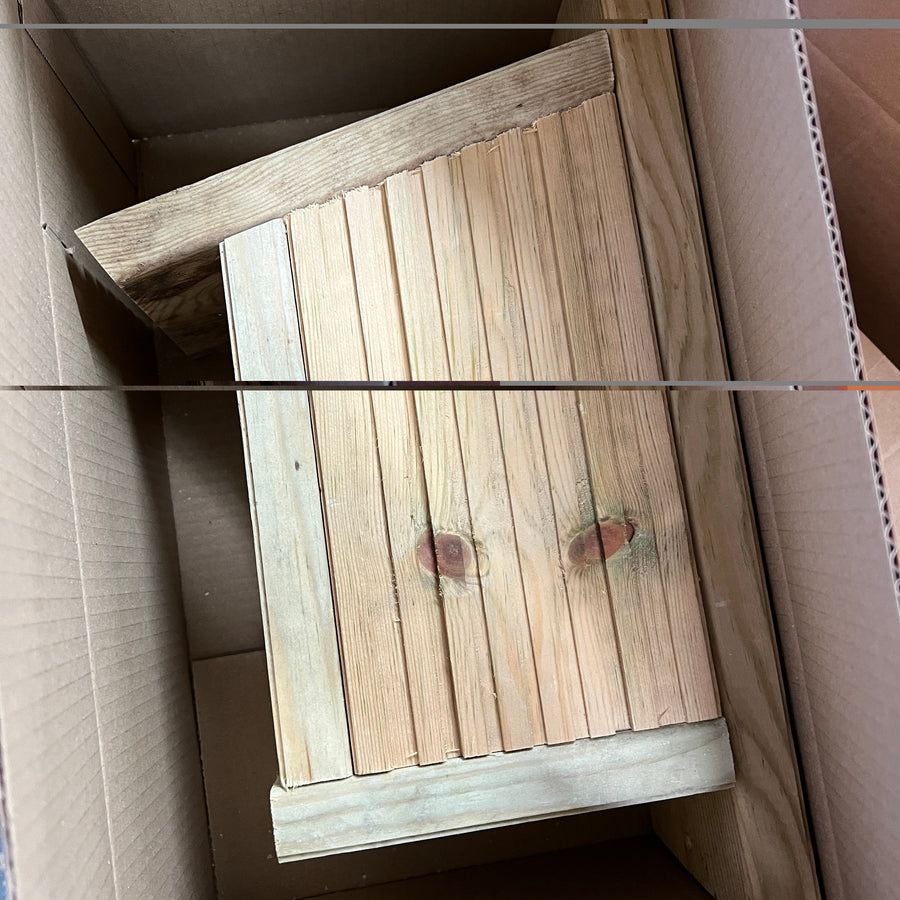 Side view of a wooden bird nesting box in protective packaging