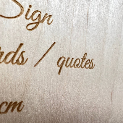 Close-up of engraved script lettering on a birch plywood sign