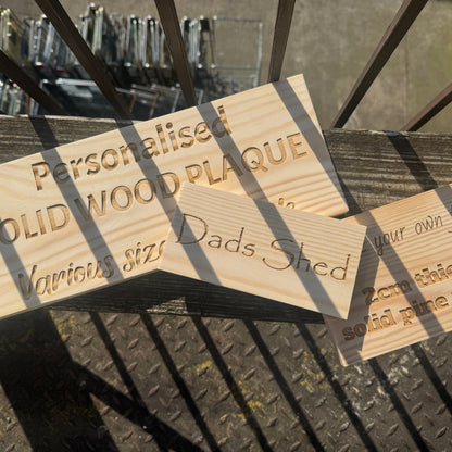 Personalised pine plaques displayed outdoors, including a Dad's Shed sign