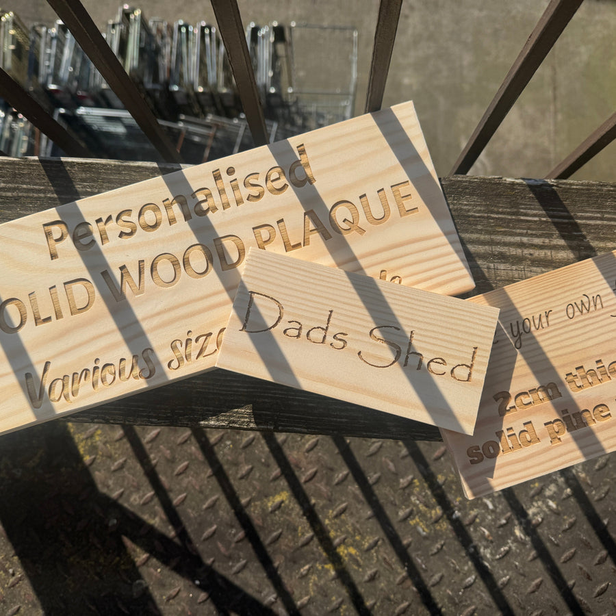 Personalised pine plaques displayed outdoors, including a Dad's Shed sign