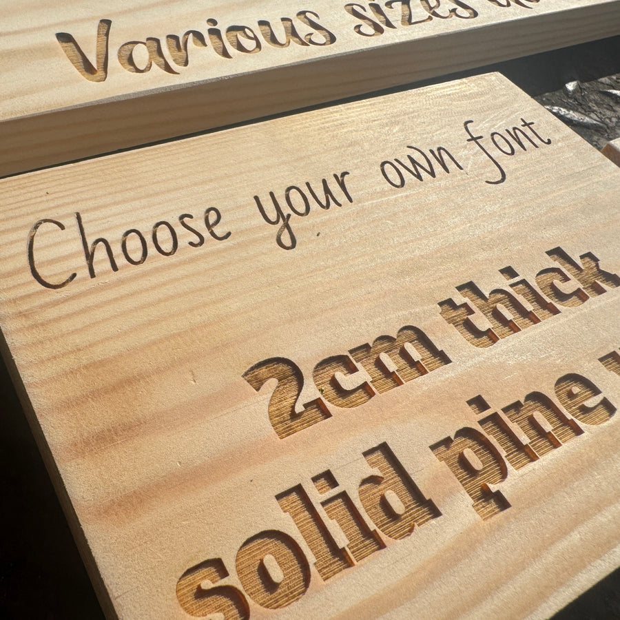 Close-up of engraved lettering on a solid pine plaque showing 2 cm thickness