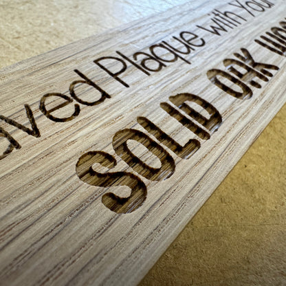 Close-up of lettering engraved into a solid oak plaque