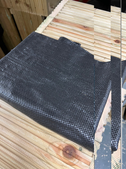 Folded black planter liner laid on wooden boards