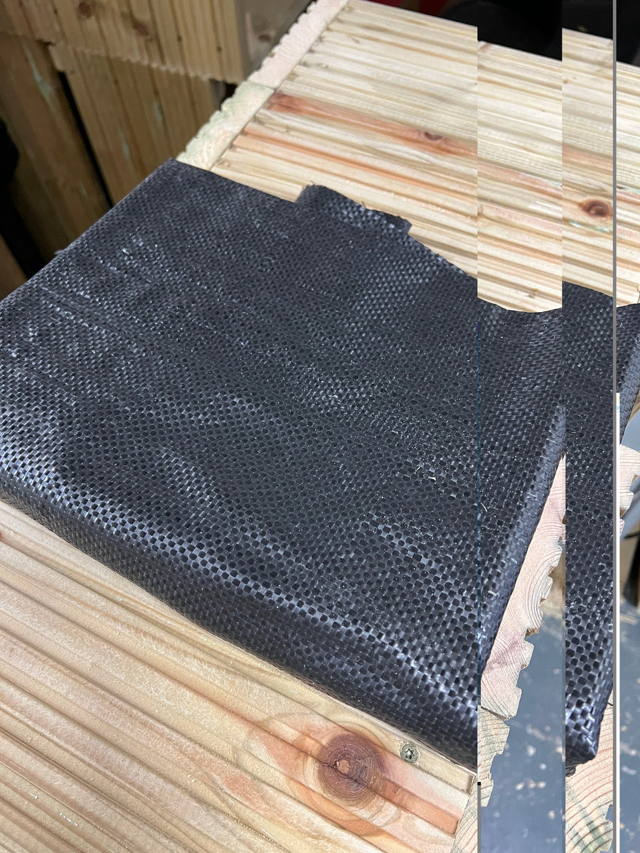 Folded black planter liner laid on wooden boards