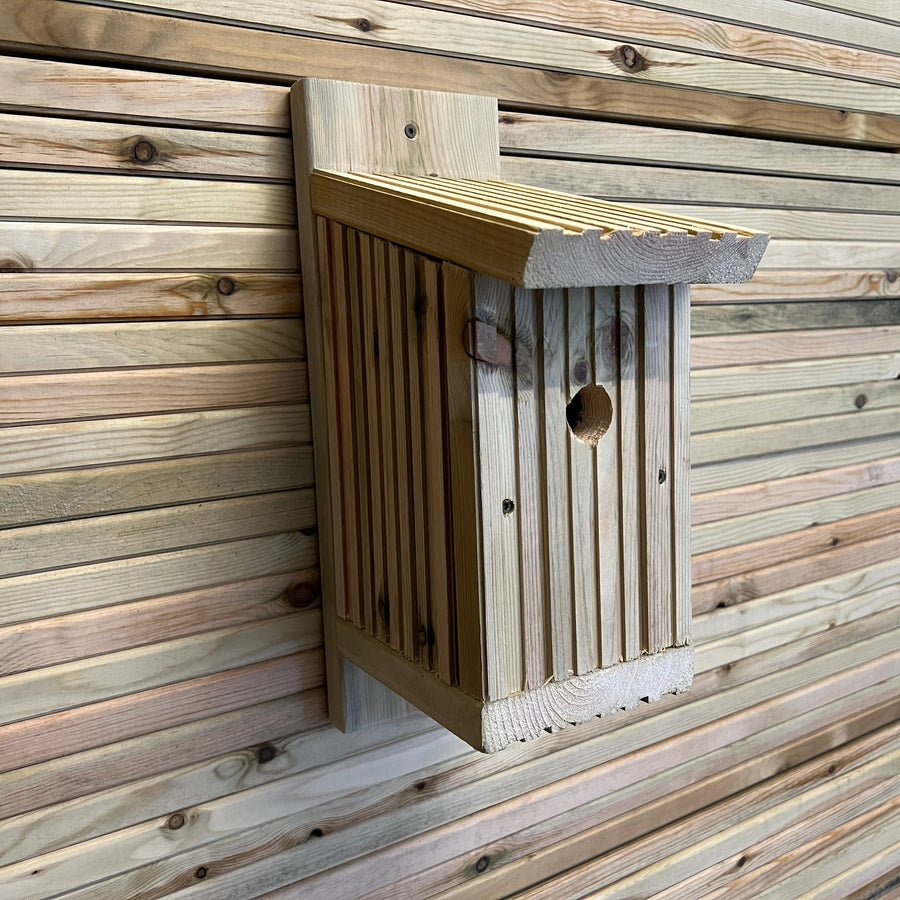 Angled side view of a wooden bird nesting box