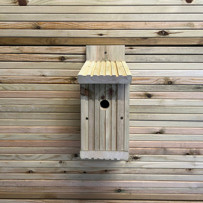 Front view of a bird nesting box mounted on horizontal timber boards