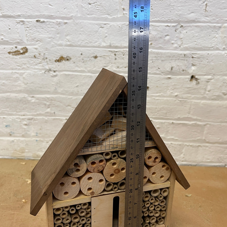 Wooden insect hotel beside a ruler for scale
