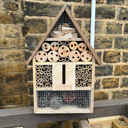 Wooden insect hotel displayed outdoors against a brick wall
