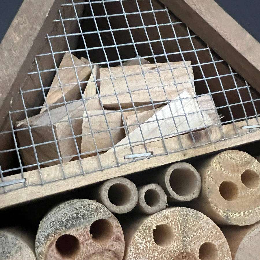 Close-up of the bug hotel's upper chamber, wire mesh and drilled wood