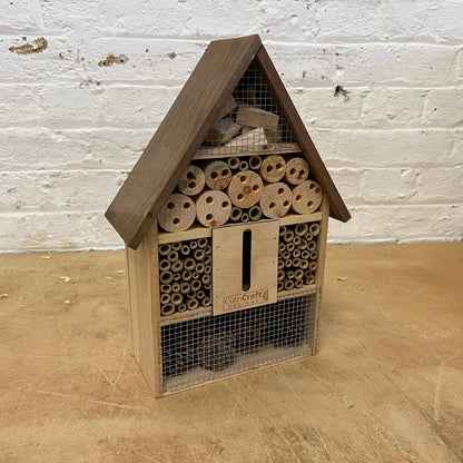 Wooden bug hotel with bamboo tubes, drilled wood and a butterfly slot