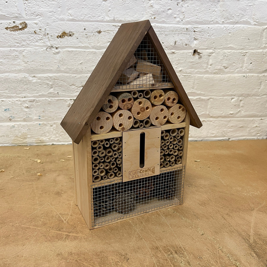 Wooden bug hotel with bamboo tubes, drilled wood and a butterfly slot