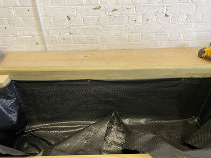Black planter liner fitted along the inside wall of a wooden planter
