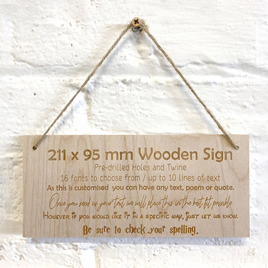 Personalised wooden sign with twine cord hanging against a white brick wall